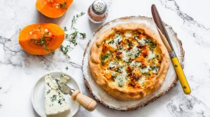 Quiche s bundevom i špinatom ženska osoba za radnim stolom jede hamburger