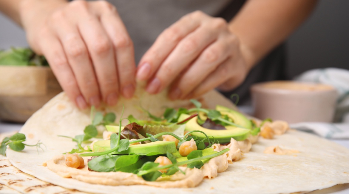 Tortilja s humusom ženska osoba za radnim stolom jede hamburger